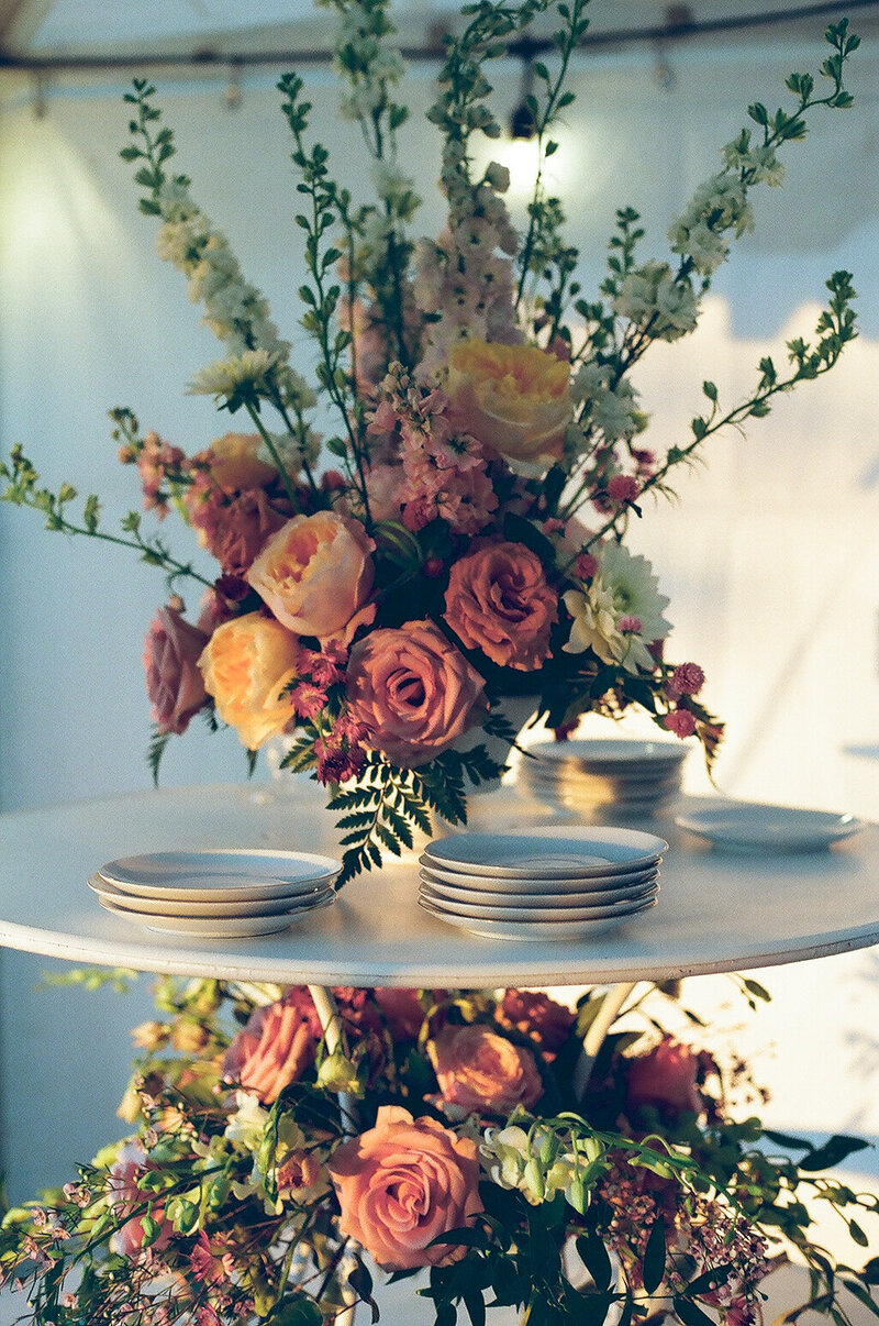 A beautifully decorated wedding table featuring a large floral bouquet, elegant plates, and refined details, set for a celebration.