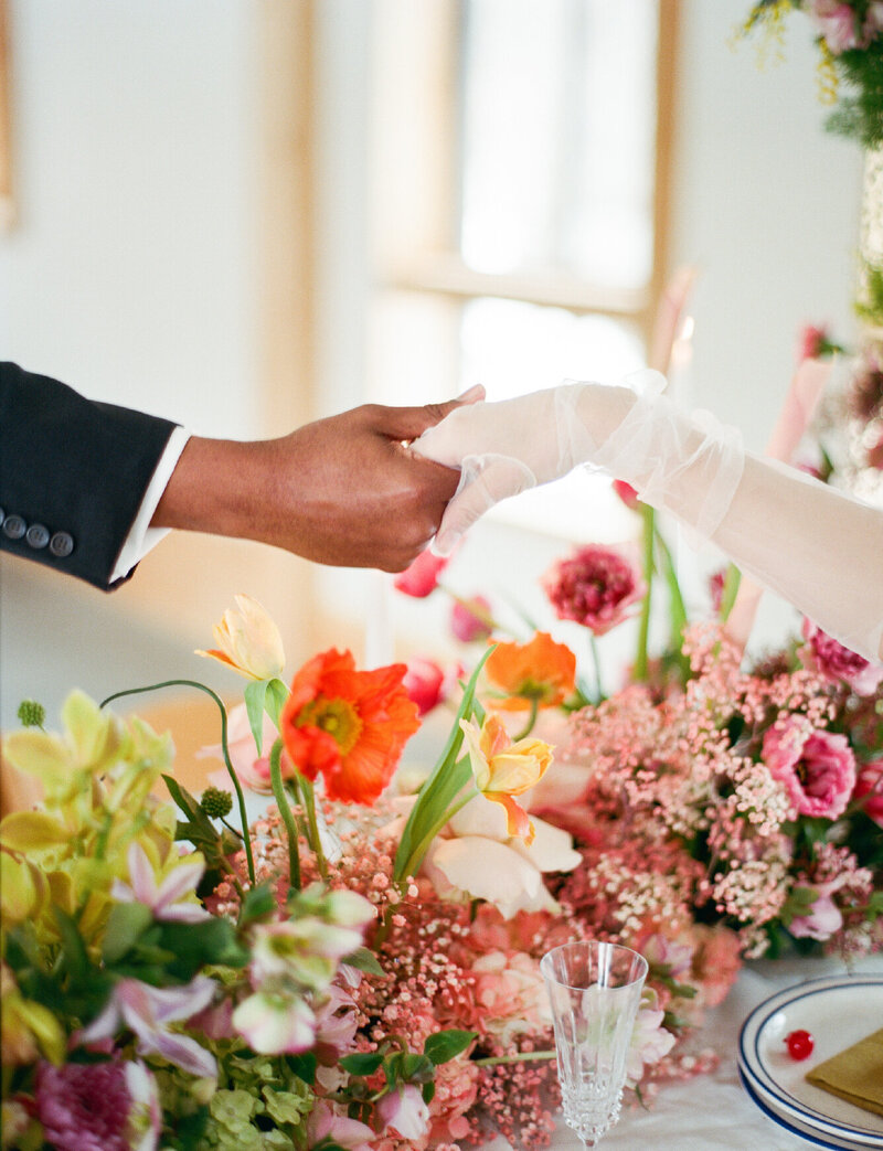 groom-holding-brides-hand-over-flower-display