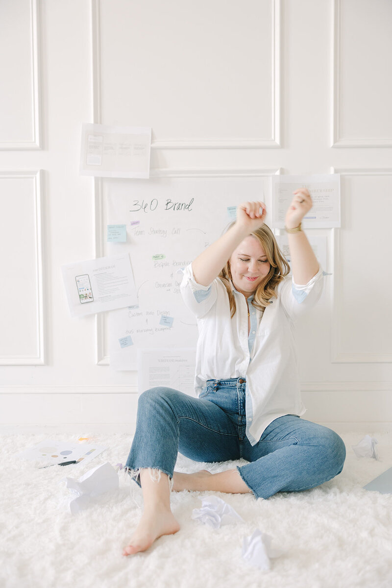 Lizzy Grant sitting on cozy rug dancing while doing brand strategy