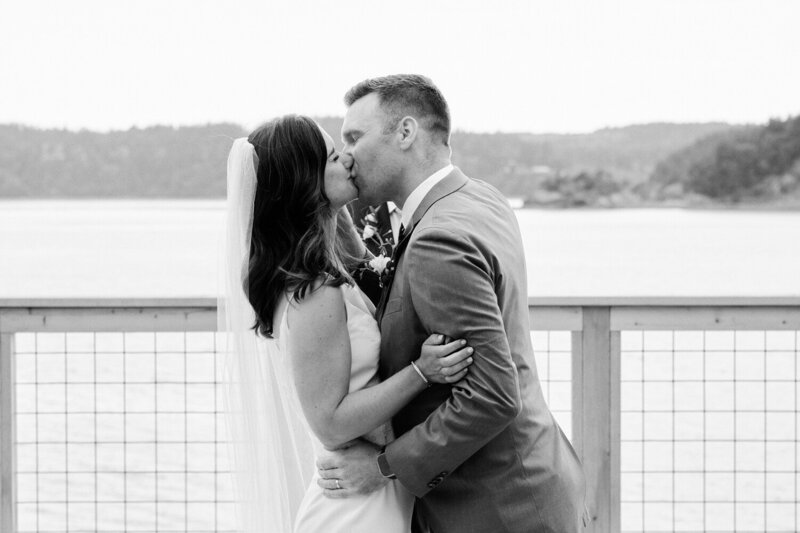 Bride and groom kiss on a platform overlooking the Puget sound