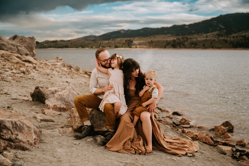 A family of 4 cuddle and enjoy each other at Horsetooth Reservoir in Fort Collins, Colorado