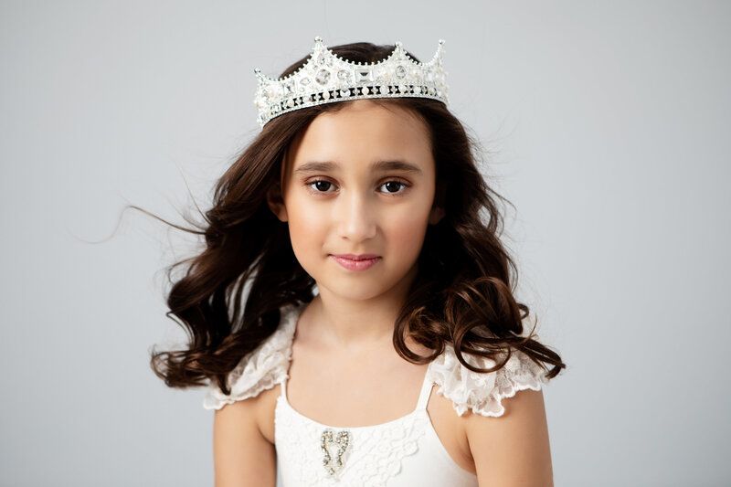 Beauty portrait of a little girl wearing a crown in a white dress