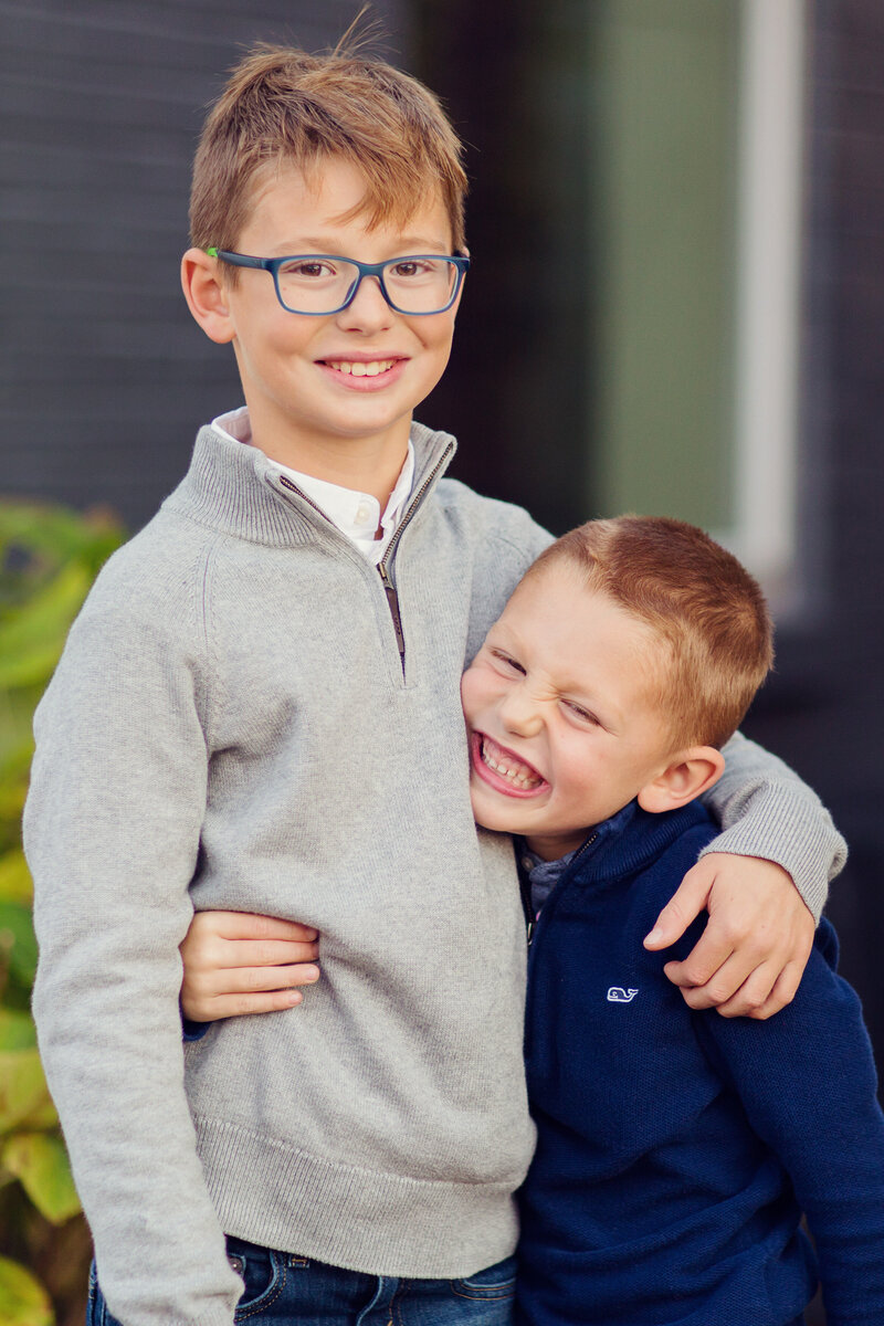 Brothers in gray and blue sweaters looking at the camera smiling in Zionsville, Indiana.