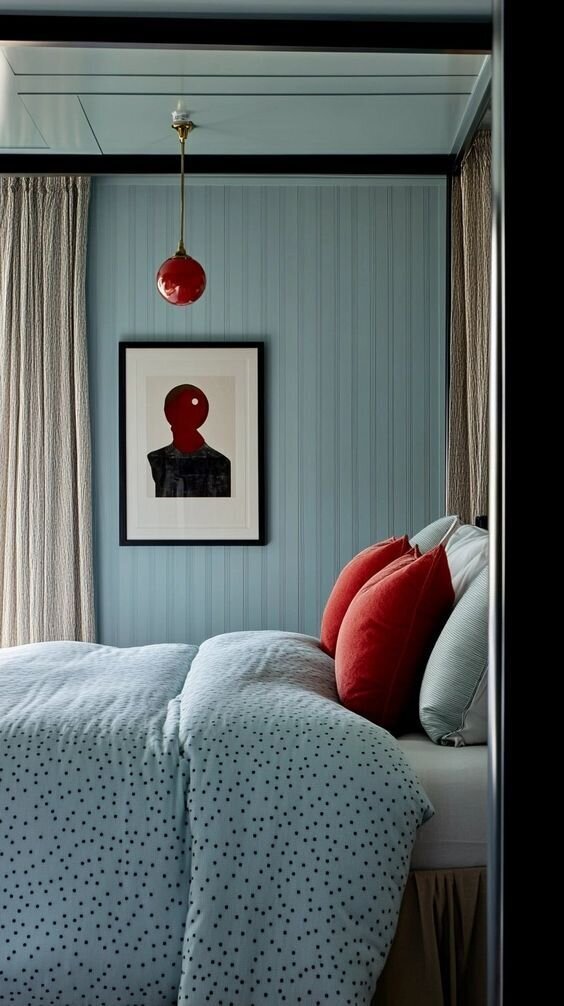 A cozy bedroom featuring blue walls and a vibrant red and white bed, creating a striking color contrast.