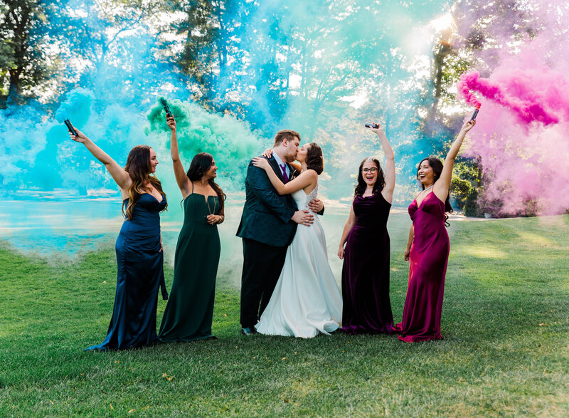 wedding party posing on golf course with smoke bombs