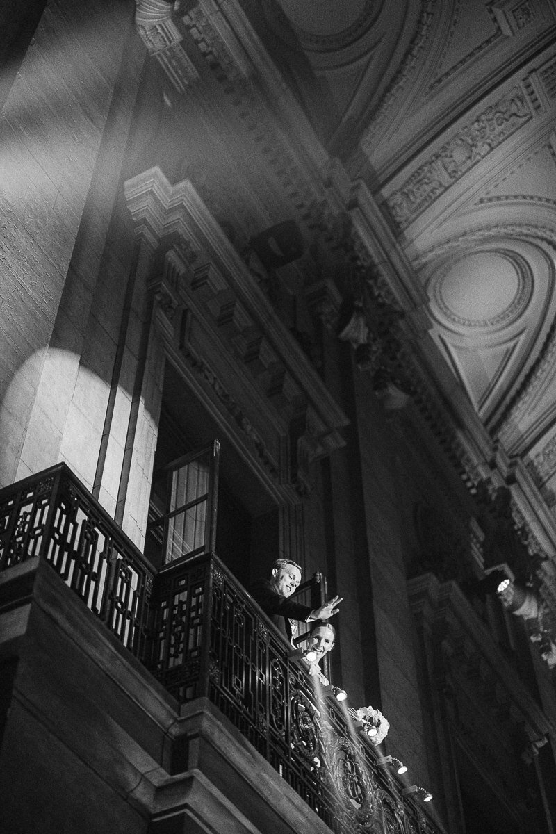 The newlyweds are welcoming their guest form the balcony at Théâtre St-James, Old Montreal. Elegant wedding venue in Montreal.