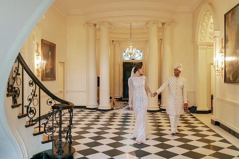 Couple holding hands  as they walk through the Swan House
