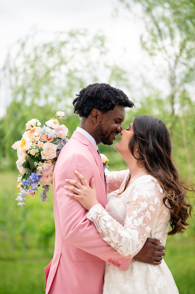Danvy and Antoni embrace on wedding day in pink suit and floral embroidered wedding dress