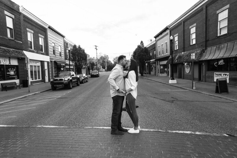 Engaged couple stops to kiss in the crosswalk of downtown Edinboro PA