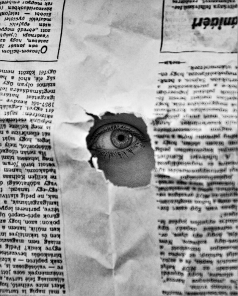 eye poking through newspaper