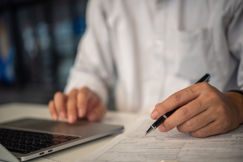 Image of a man with a computer and pen working on tax preparations