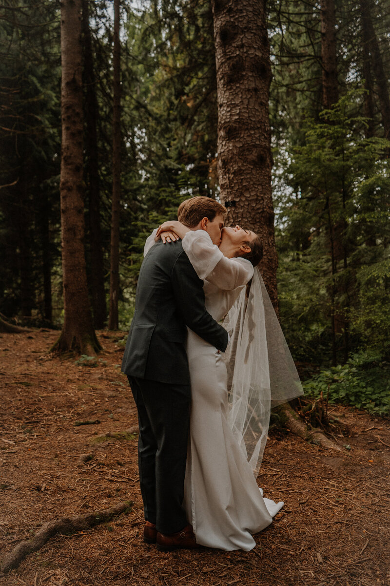 Groom kissing bride's neck in a forest