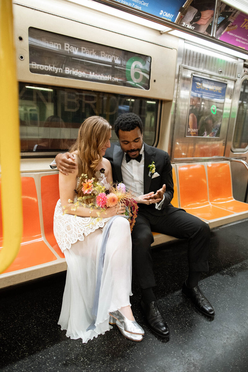 NYC city hall elopement looking at wedding rings on subway