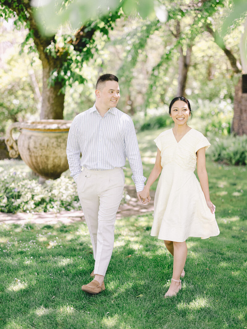 Engaged couple walking through garden for pre-wedding portraits