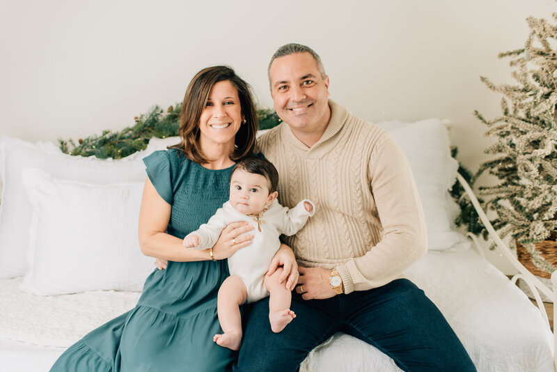 Family of three smiling at the camera at their indoor family session