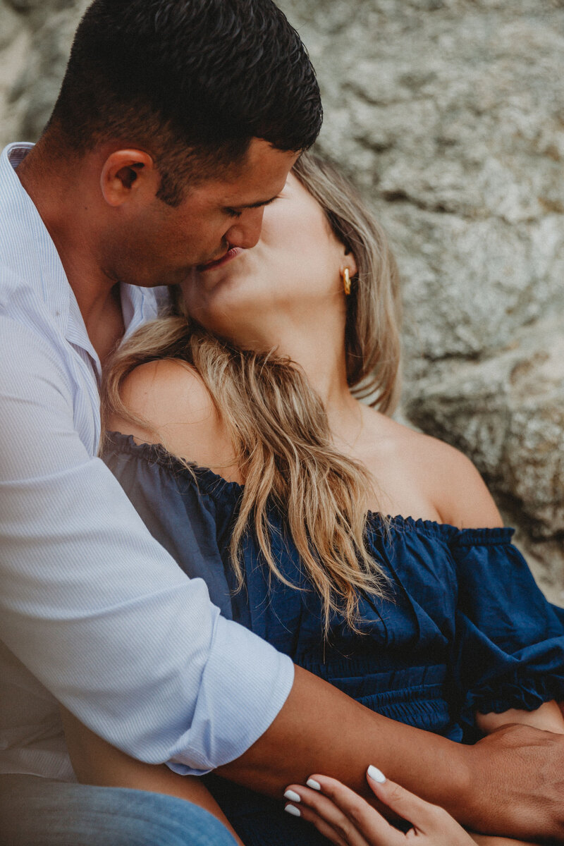 big sur engagement session with couple sitting on beach kissing