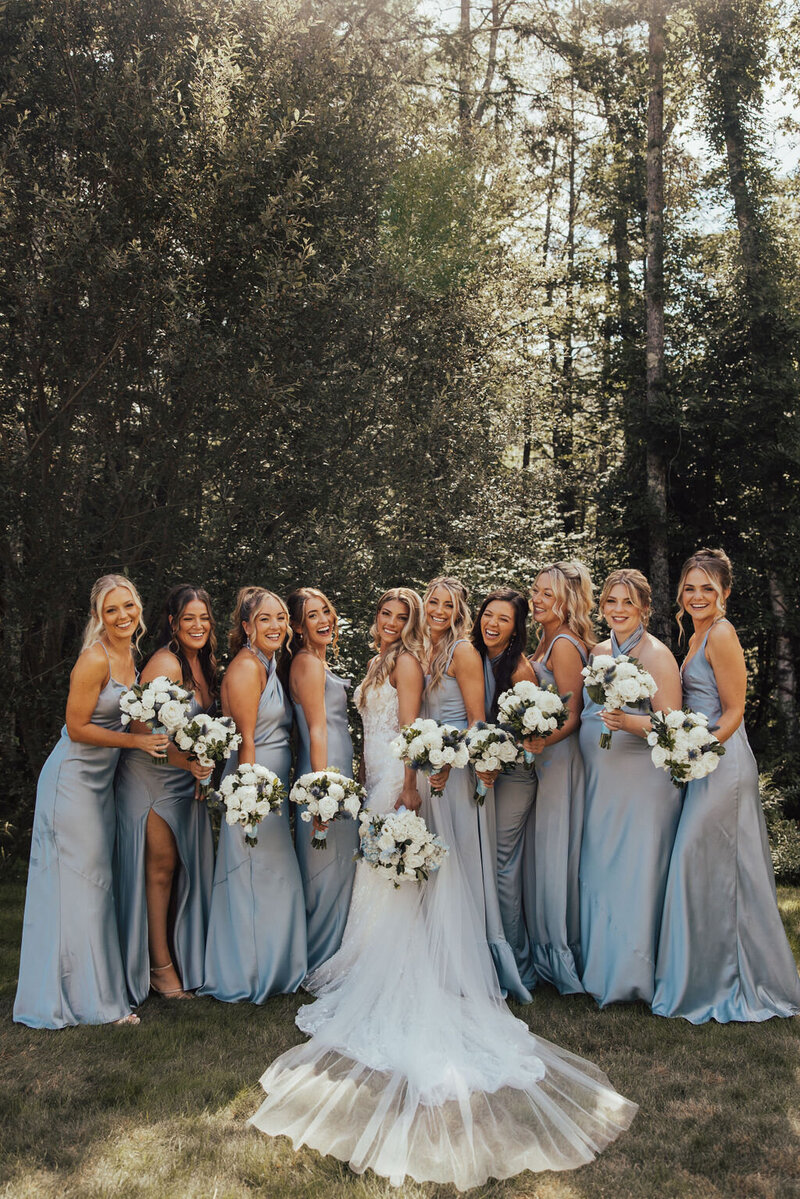 Bride and bridesmaids holding bouquets smiling at the camera