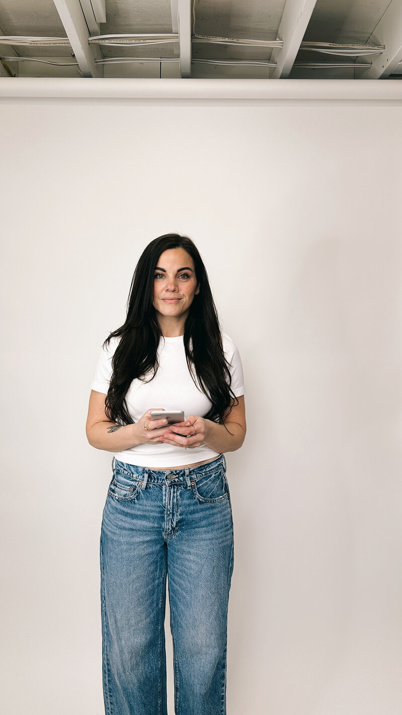 A woman holding a phone, looking directly at you