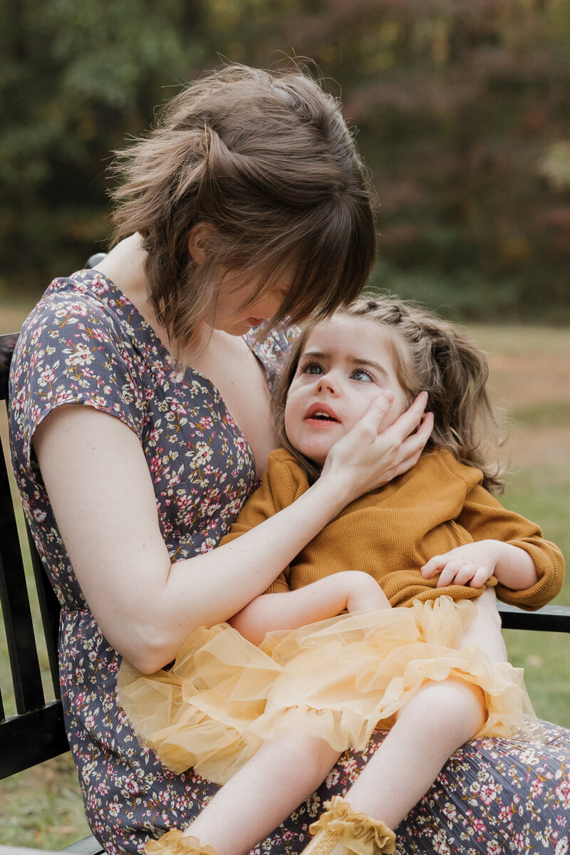 Parents smiling and holding their baby during a sunny Raleigh family photo session captured by Moments by Hiba.