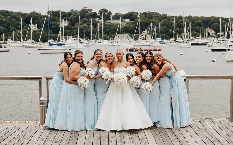 bride with  bridesmaids in light blue matching dresses on dock