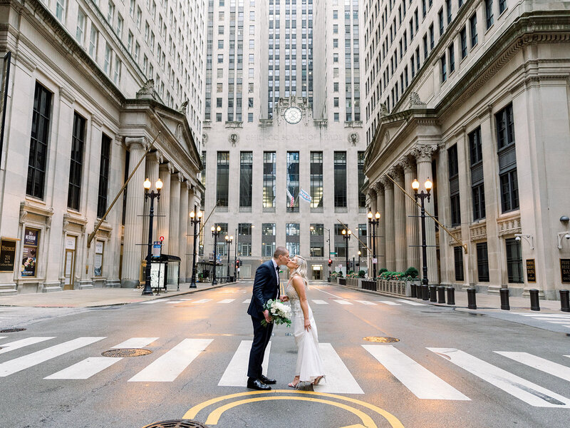 bride and groom kissing by board of trade