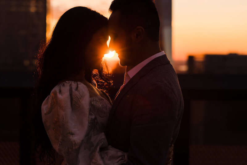 Bride and groom embrace at sunset on a Manhattan rooftop, the golden sun between them, captured by NYC wedding photographer Heritage House.