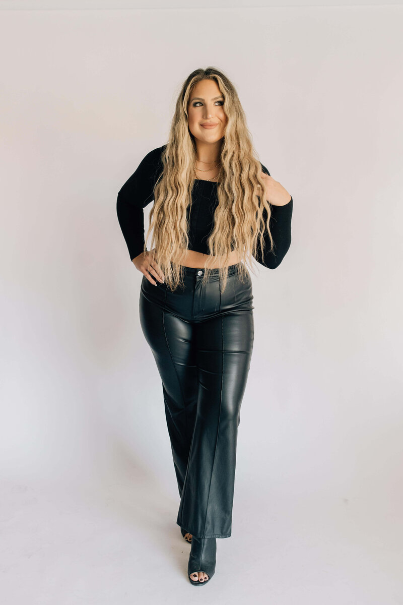 Headshot of certified hair stylist with blond hair extensions smiling wearing black