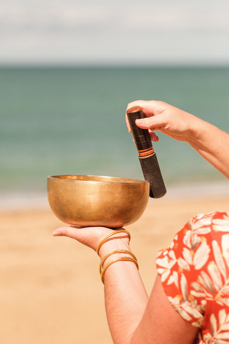 Natacha faisant sonner un bol tibétain à la plage  lors d'un soin sonore.