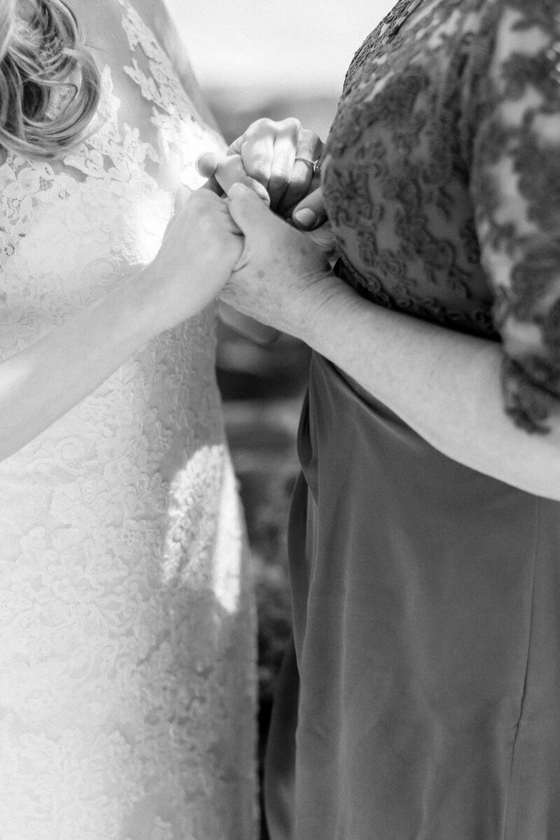 Bride and her mother holding hands