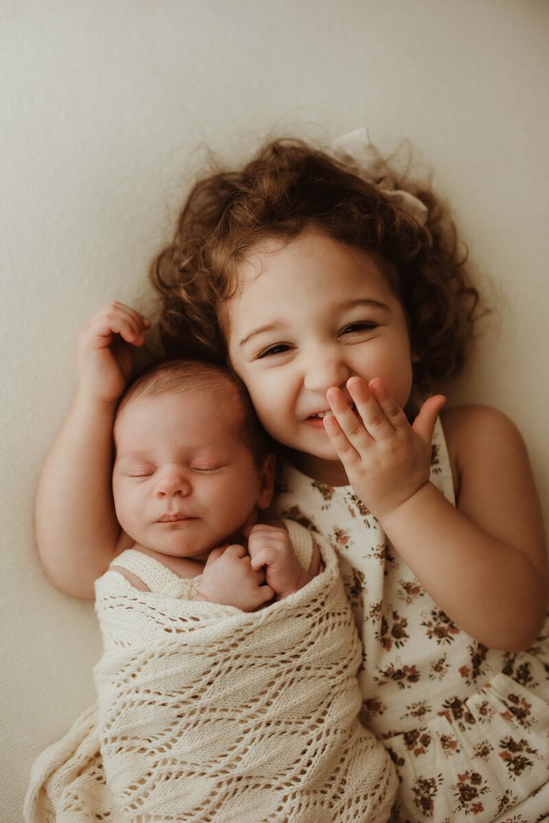 Newborn baby with big sister photographed indoors in soft light, Sydney newborn photographer Sophie Lea.