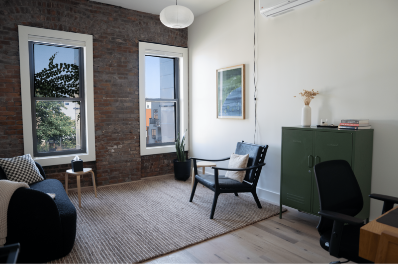 Sunny, furnished therapy office in Greenpoint, Brooklyn with brick walls and large windows with a view.