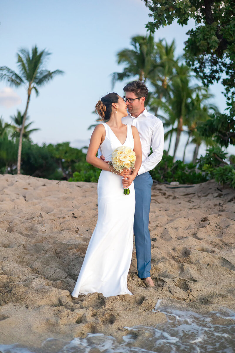 bride and groom kissing on the beach at sunset