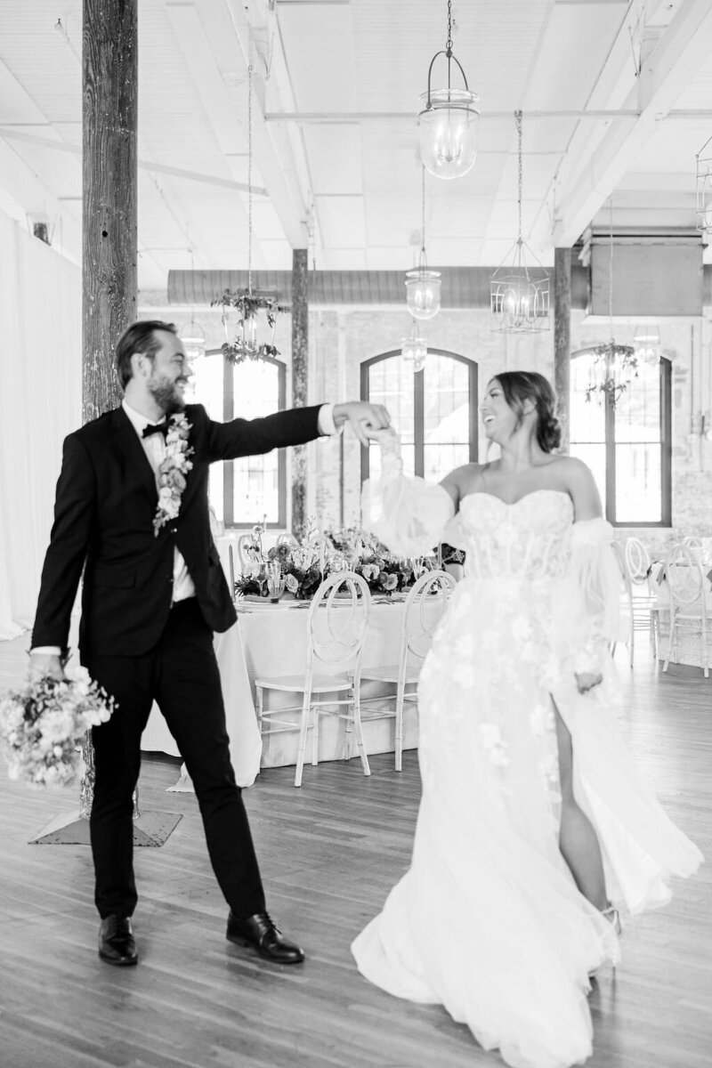 A joyful bride and groom share a romantic dance at their luxury wedding at The Cedar Room in Charleston, SC. A timeless black-and-white moment filled with love and elegance.