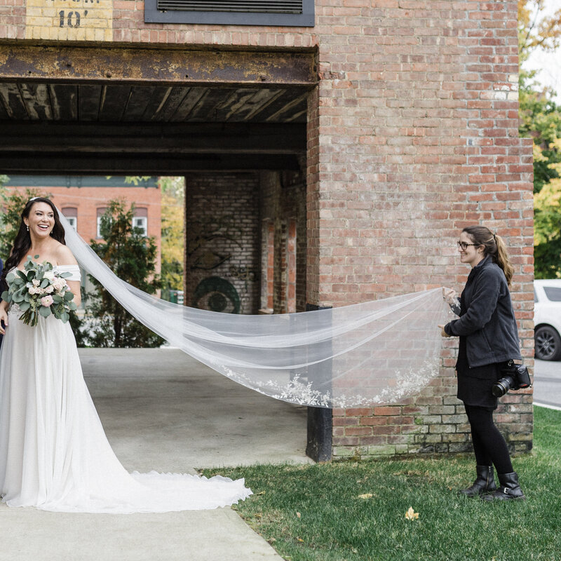wedding photography assistant holding brides wedding veil
