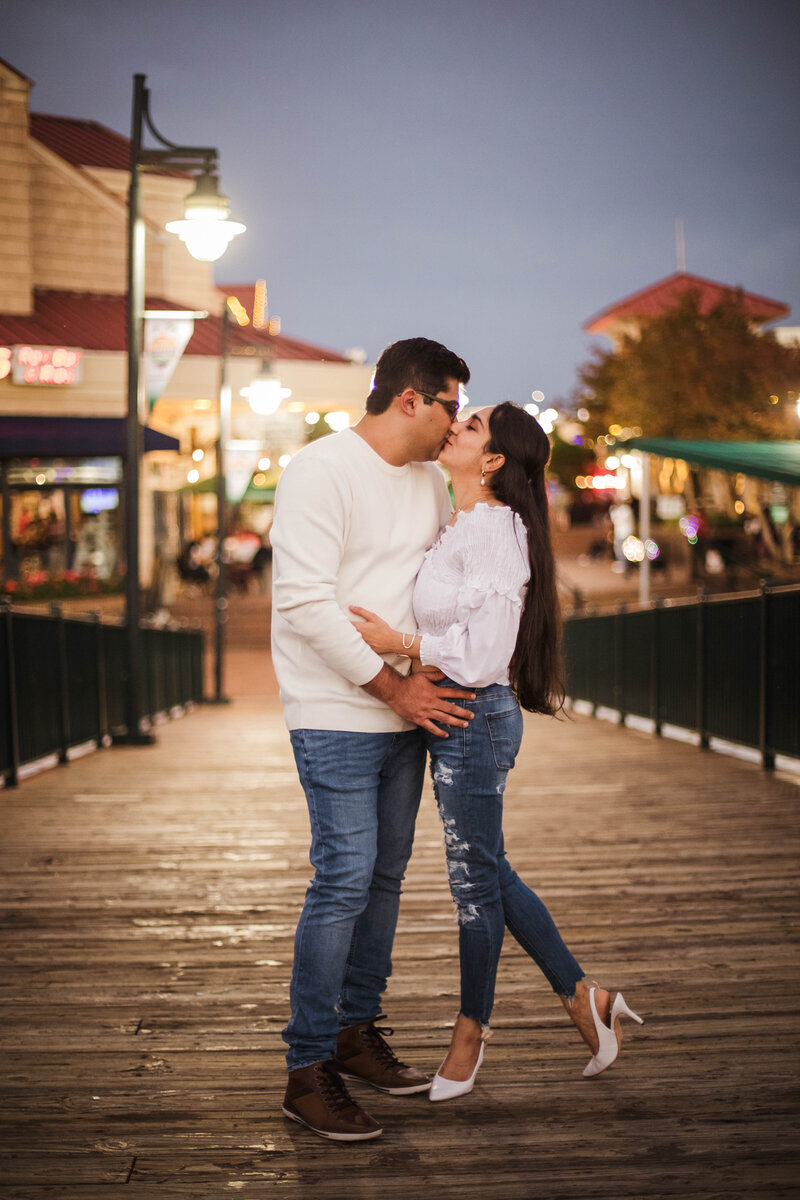couple kissing on boardwalk during engagement session