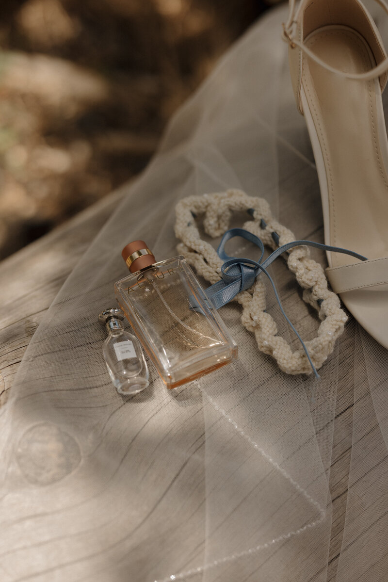 A refined wedding detail shot featuring an elegant bridal perfume bottle, styled in soft, romantic light for a luxury destination wedding.
