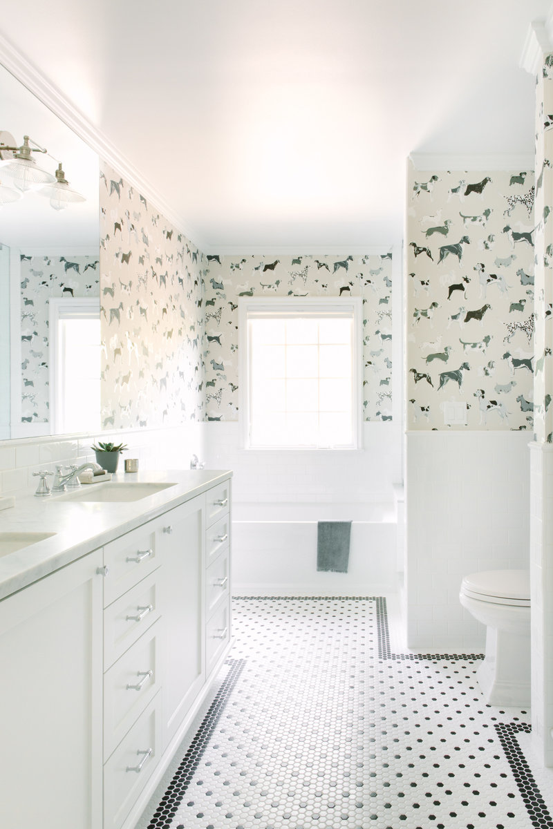 Boys bathroom with black and white hexagon floor tile, white subway tile, Carrara marble counter, and dog wallpaper