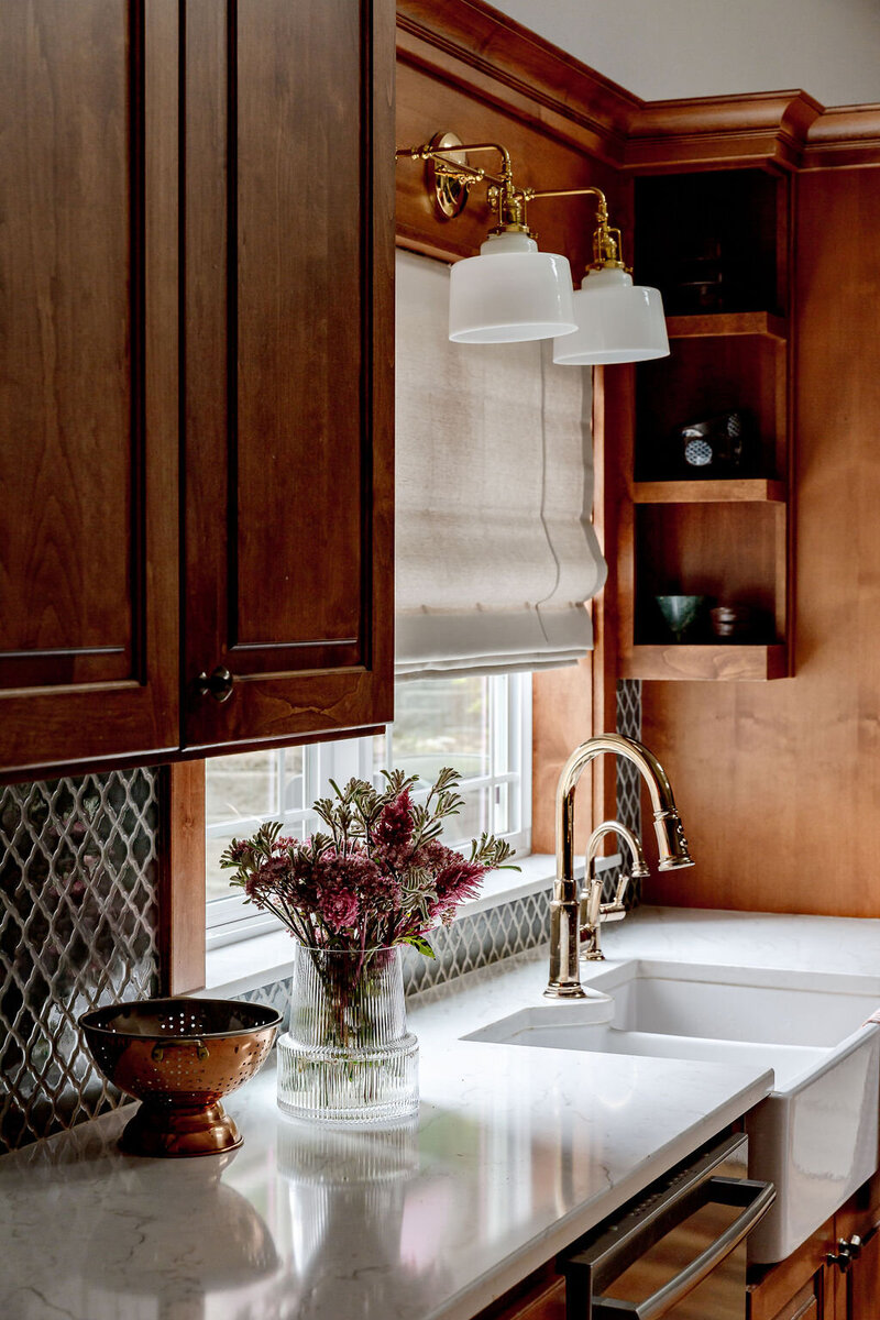 A close up of a kitchen counter featuring a farm sink and wooden cabinets showcasing a farmhouse interior design.