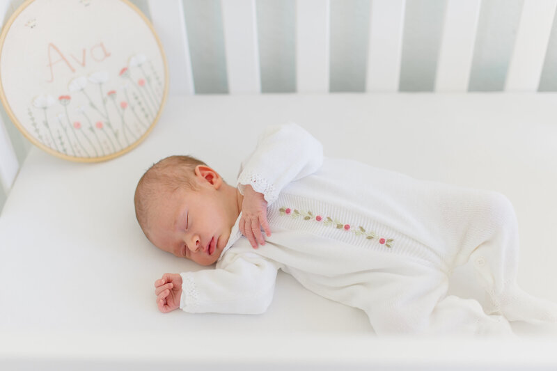 Sweet babygirl laying in her crib asleep while newborn photographer captures the moment