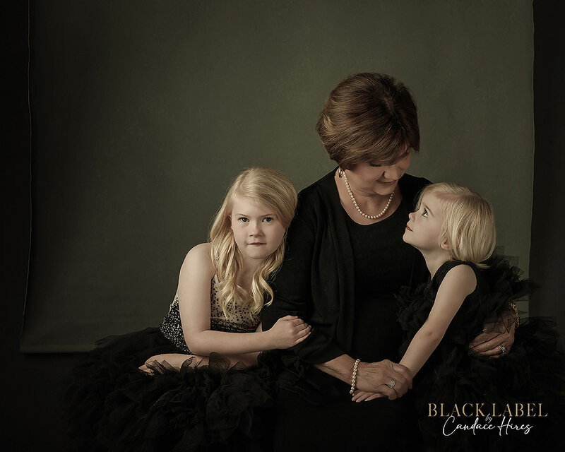 luxury portrait of a grandmother with her two granddaughters in  studio on  a layed black backdrop