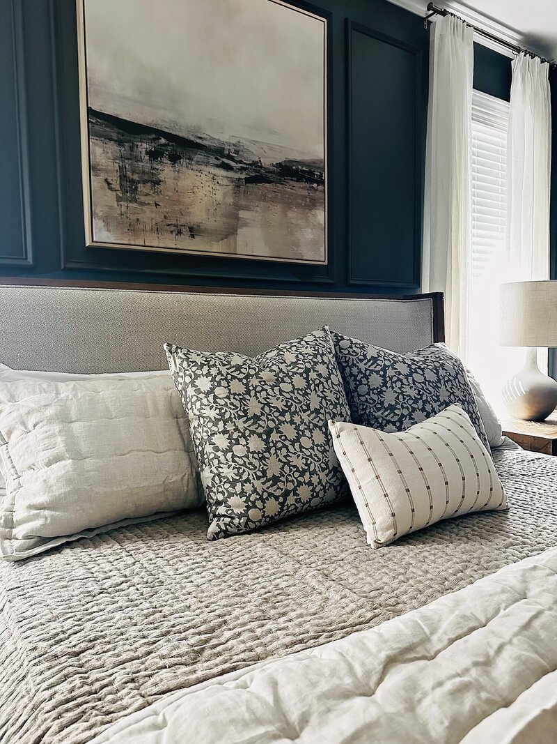 Bed with plush linens and layers of textured pillows.