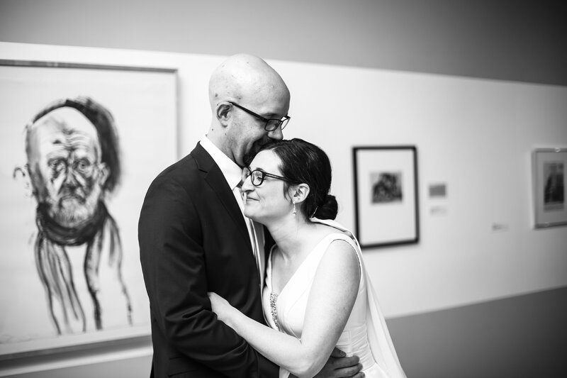 Bride and groom  embrace in the gallery of the Erie Art Museum