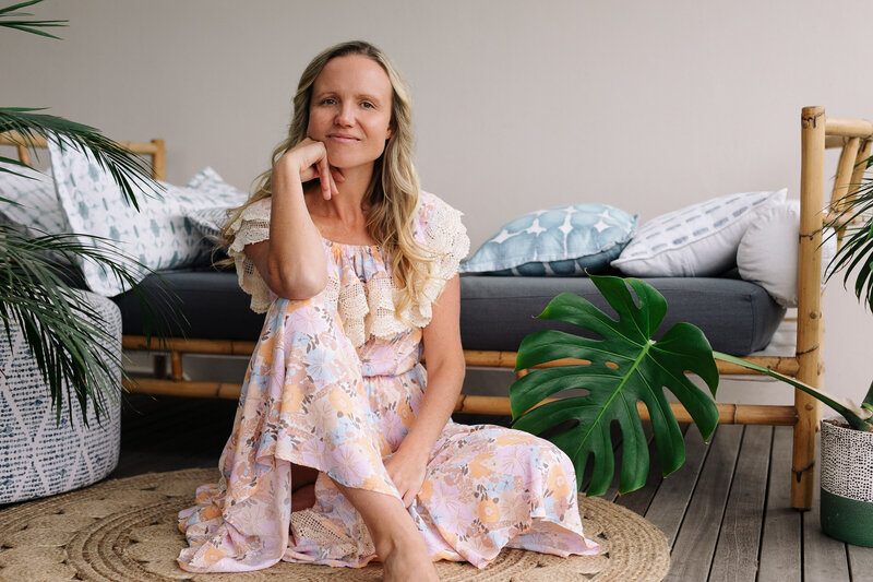 A lady with a boho inspired dress sits and looks casually at the camera