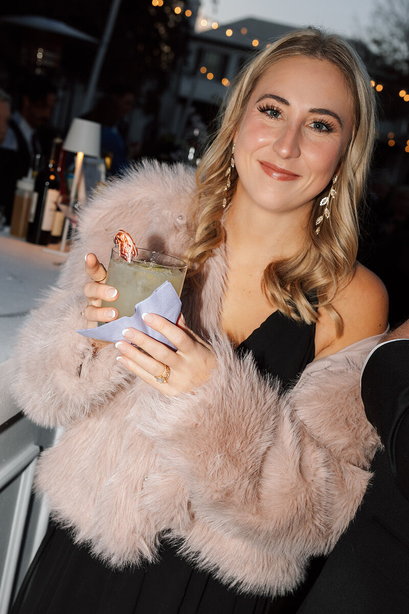 Wedding guest showing off cocktail and outfit
