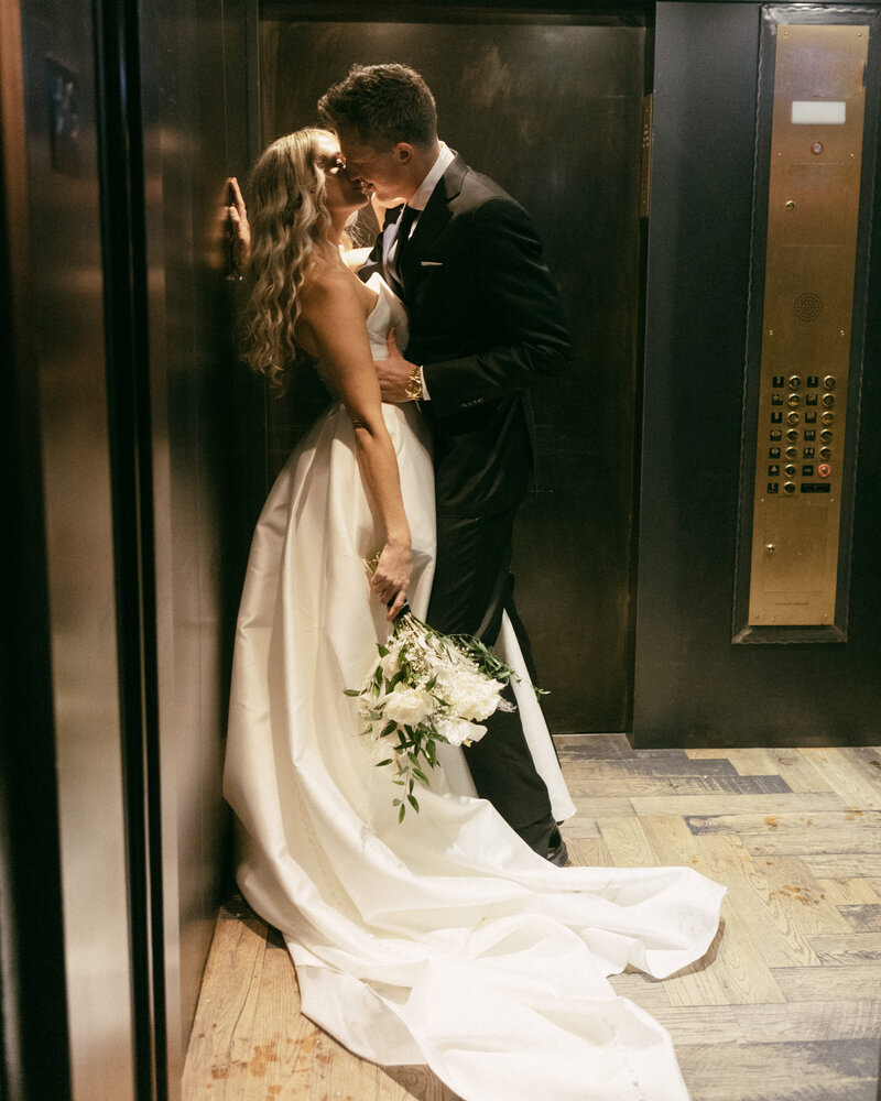 bride and groom kissing while standing in an elevator