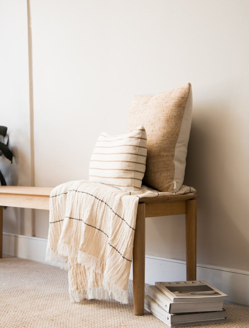 Blanket and Pillows on a neutral colored bench