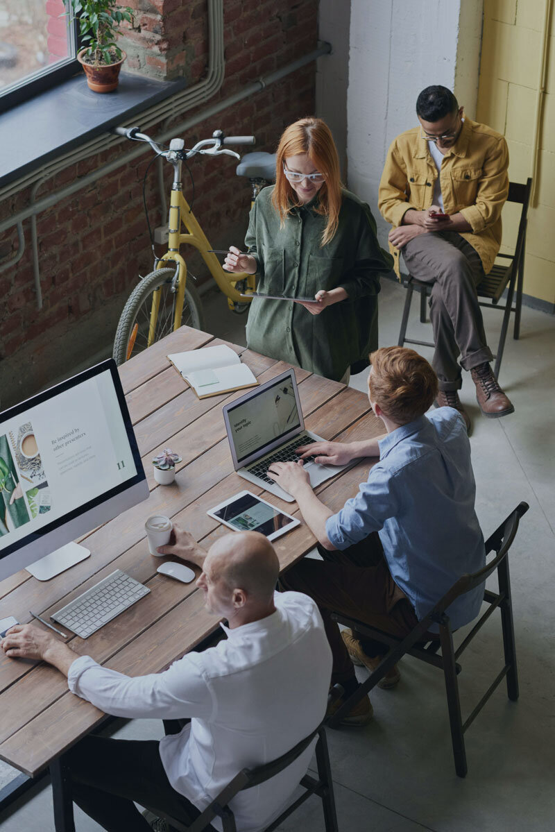 Bird's eye view of four people standing around a desk at work
