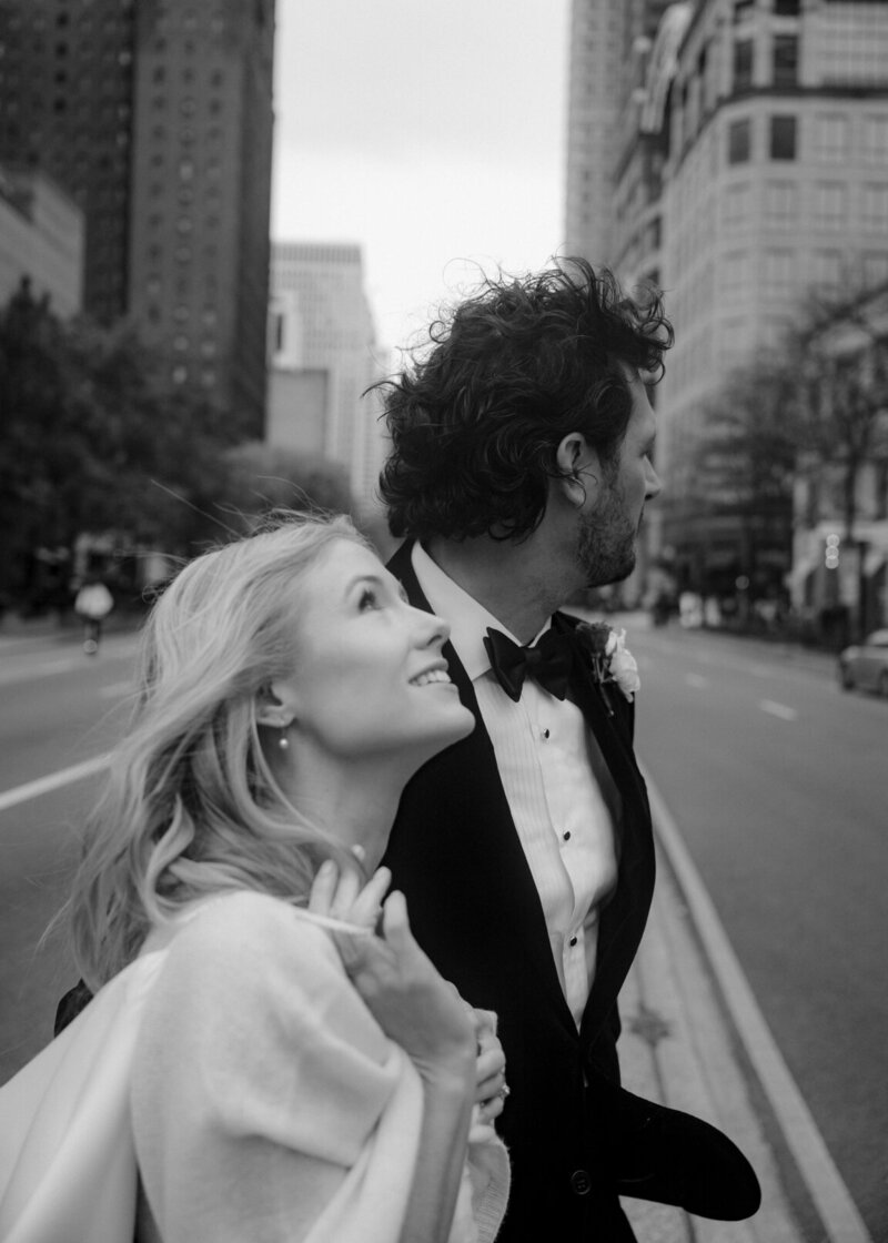 Candid photo of blonde bride and brunette groom as they cross the street on their wedding day. 