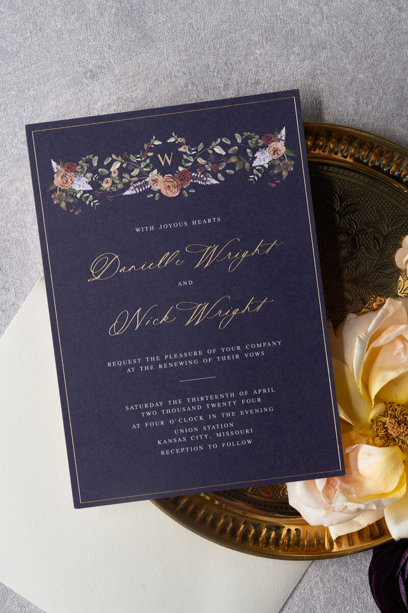 White curved menu card on a plate with a brown velvet napkin and flowers