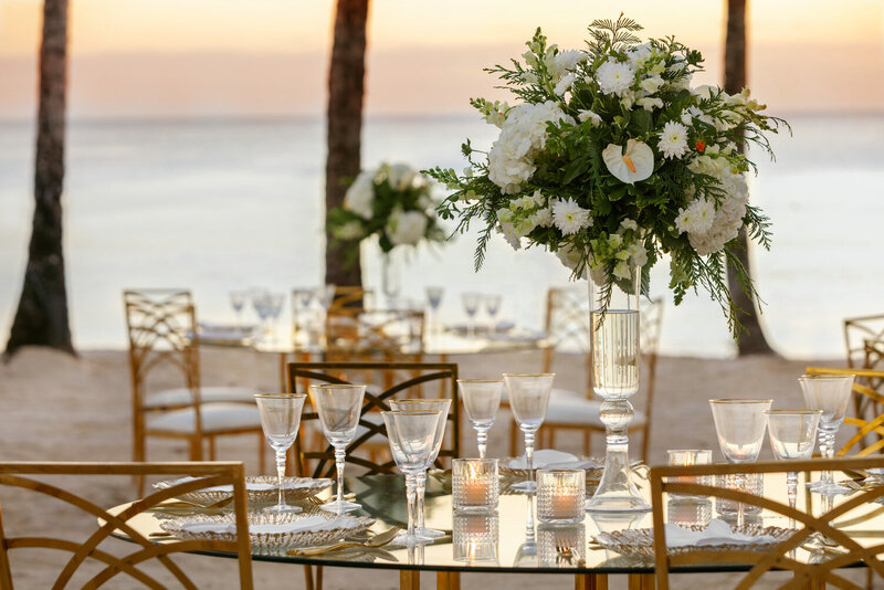 Luxurious wedding table with wine glasses, wares, and floral centerpiece by the sea